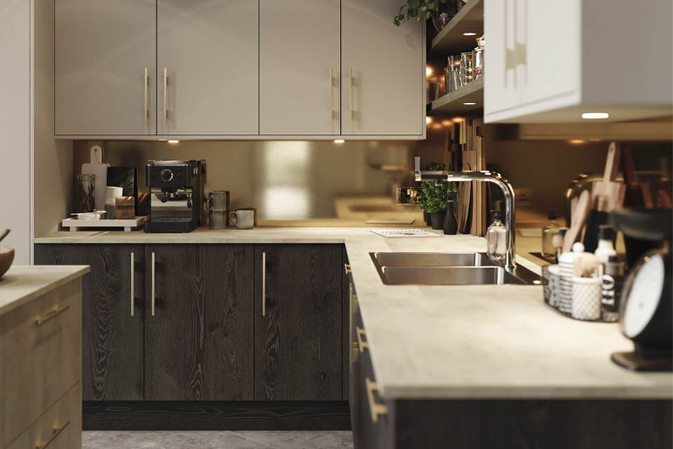 A room with black kitchen units alongside warm-looking appliances and accessories