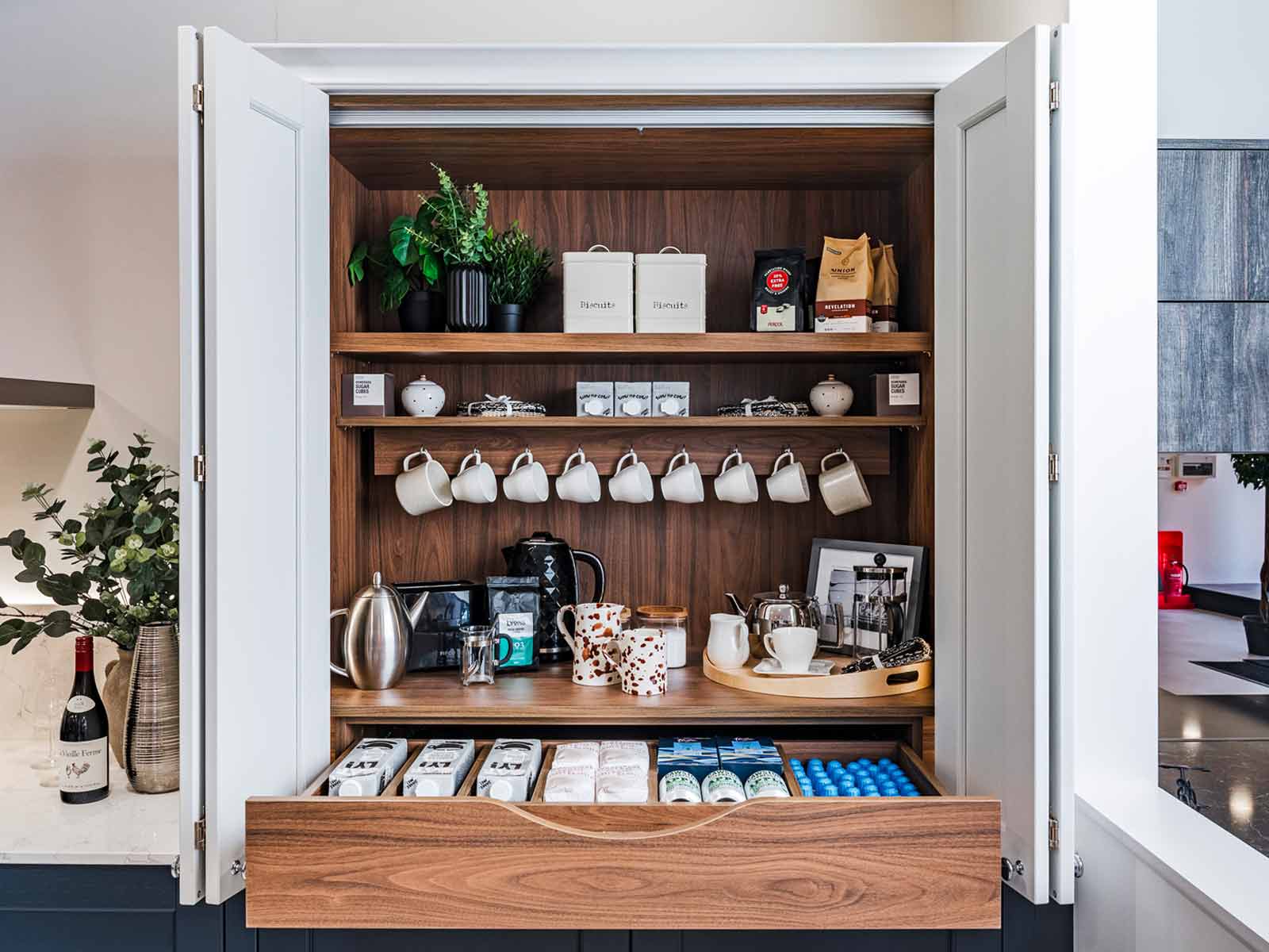 An open microwave cabinet and tea station installed in an open-concept kitchen