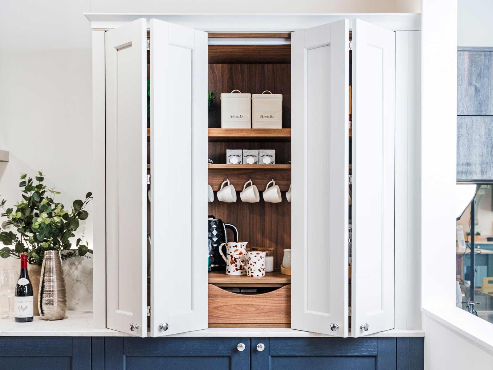 A partly closed coffee bar cabinet with tea making station facilities