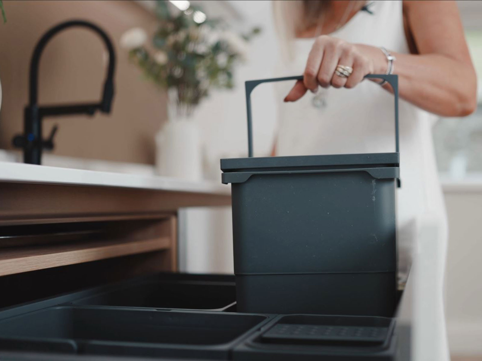 A Nordic-style kitchen with hidden kitchen bins, revealed by a woman